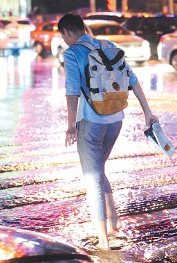 6日21點左右， 濟南遭遇急雨大風， 一時間街道變成了河流， 行人措手不及， 提鞋蹚水回家， 很多人成了落湯雞。 本報記者 周青先 攝